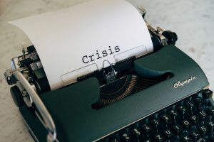 Close-up of a vintage typewriter with the word 'Crisis' typed on paper.